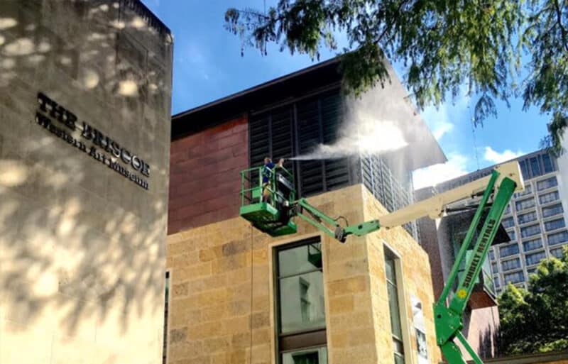 gleam team team member pressure washing a commercial building