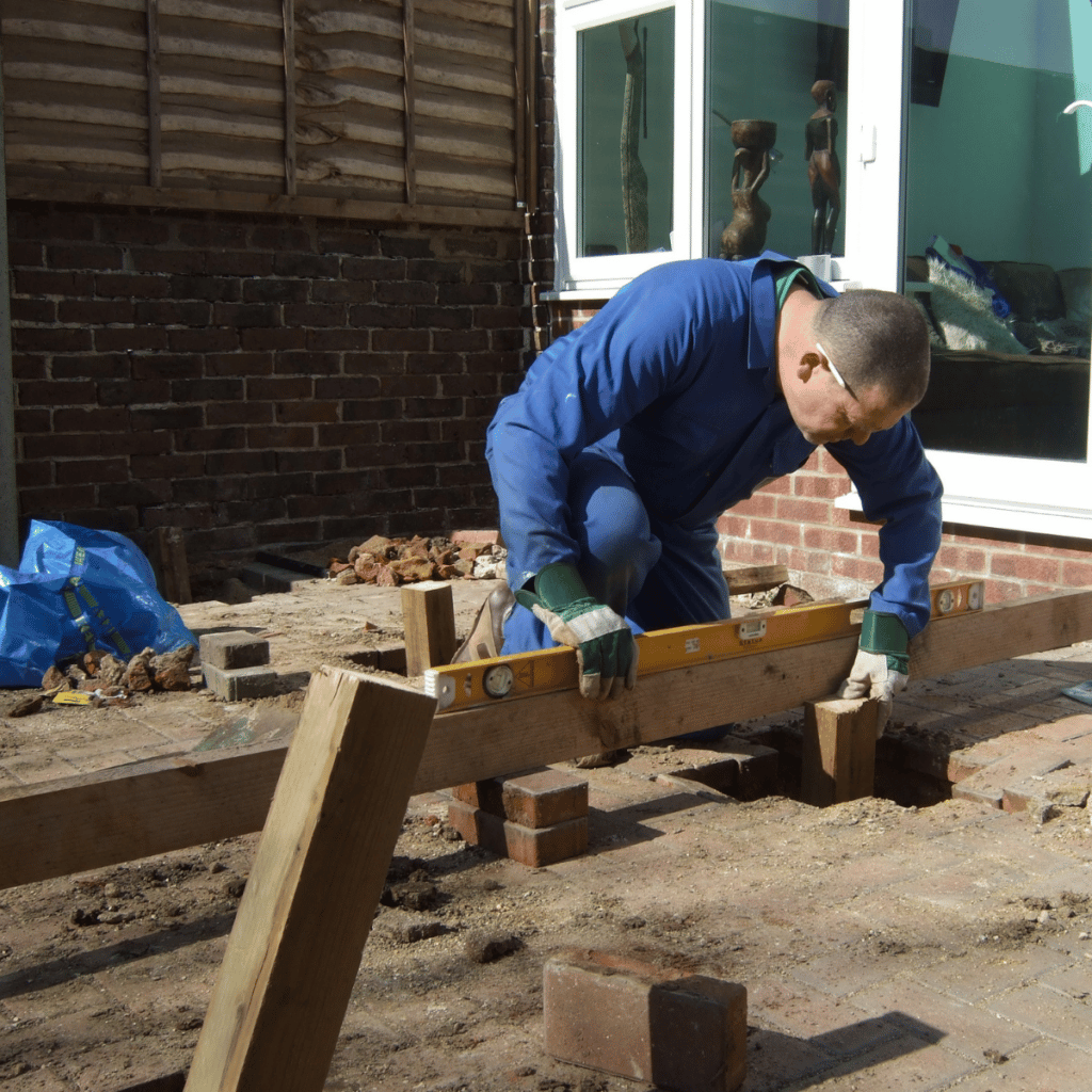 man leveling wood while restoring a deck at a house