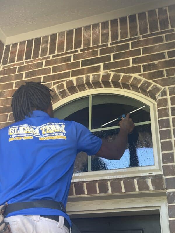 gleam team team member performing window cleaning services on residential home