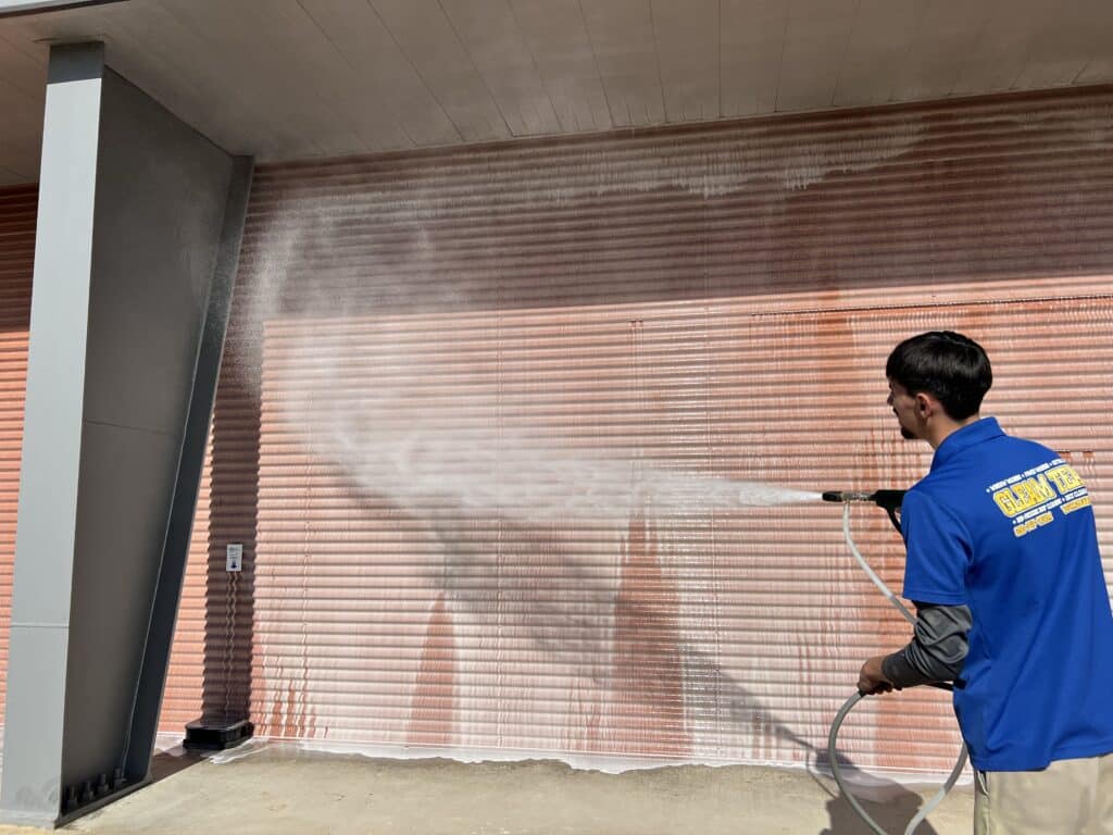 gleam team technician pressure washing a garage door with cleaning solution
