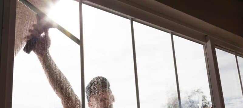 professional window cleaner using a large sponge to clean a residential window