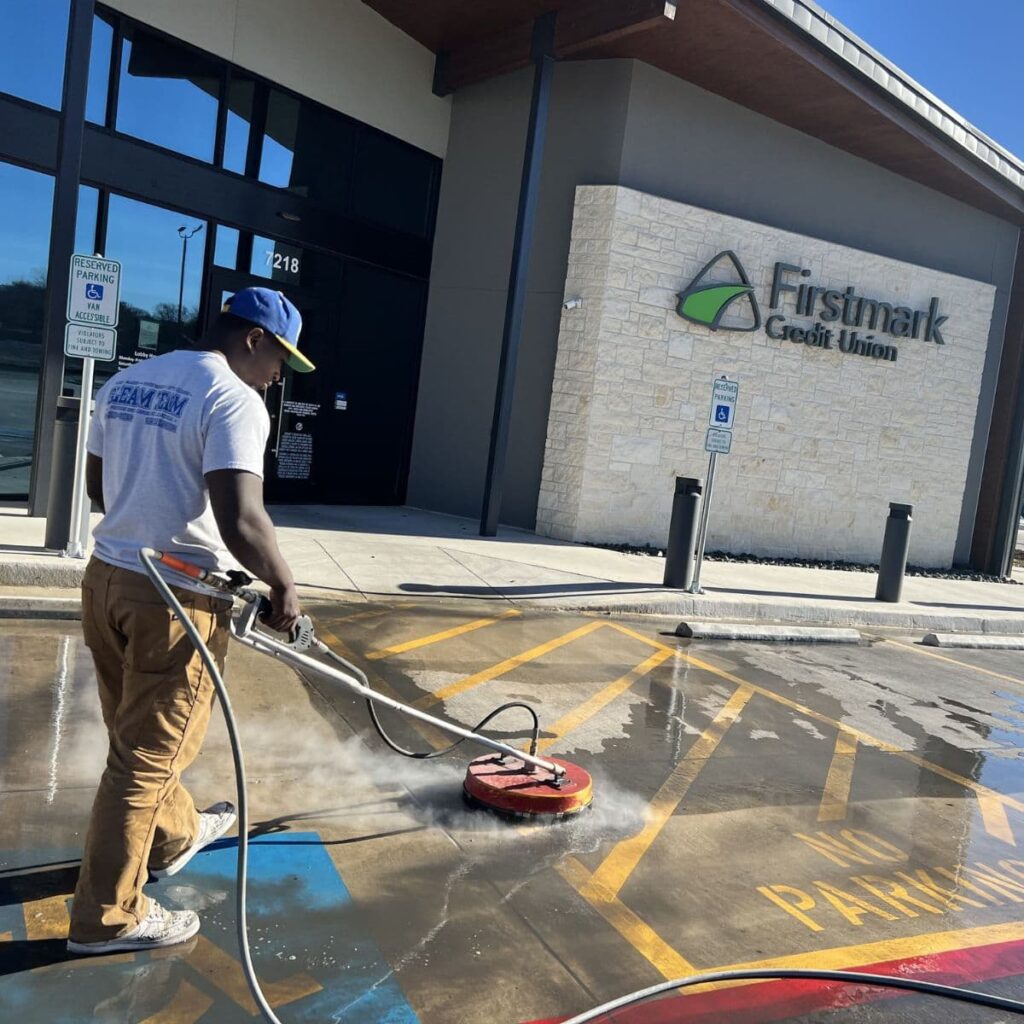 gleam team staff member pressure washing a commercial business parking lot