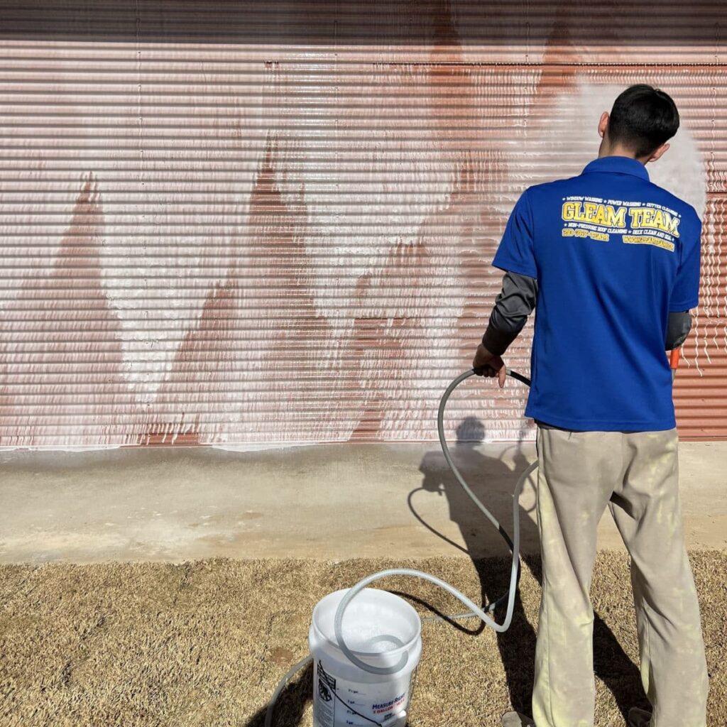 gleam team staff member pressure washing a commercial business building