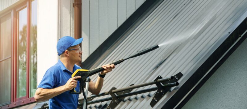 male technician power washing metal roof