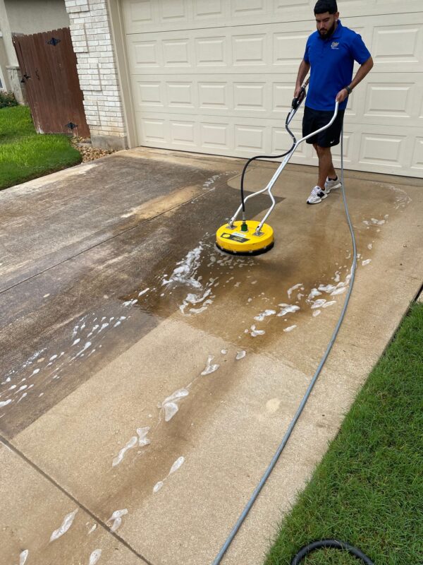 gleam team member cleaning a driveway with a pressure washer