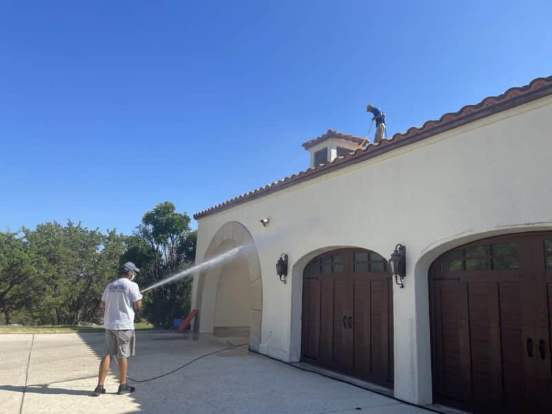 gleam team washing the exterior of a large white spanish-style house