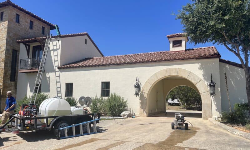 gleam team exterior cleaning performing a house washing service on a large home in san antonio